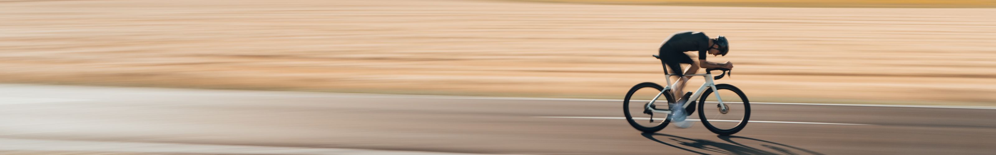 Rider in full gear aggressively cornering on a full-suspension Mondraker mountain bike, kicking up dust